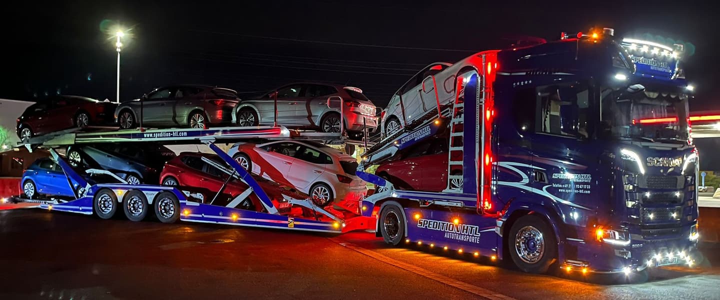 Porte-voitures Spedition HTL éclairé de nuit, chargé de véhicules de sport